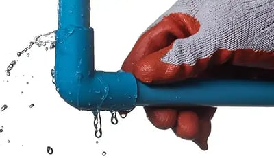 Gloved hand on a blue pipe leaking water