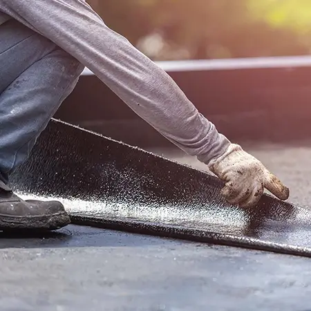 Worker installing tar foil on flat roof